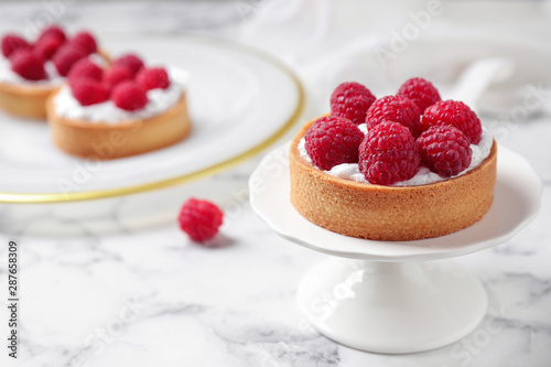 Cake stand with raspberry tart on marble table, space for text. Delicious pastries photo