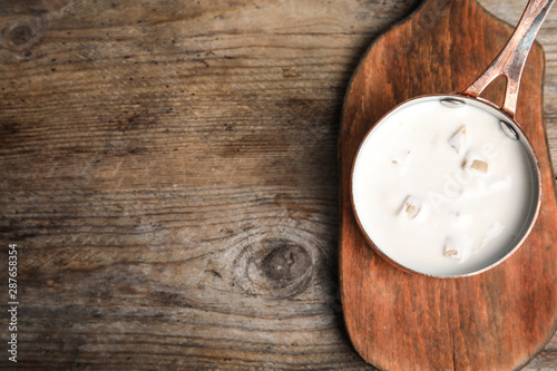 Delicious creamy sauce in pan on wooden table, top view. Space for text