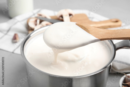 Bild auf Leinwand Spoon and pan with delicious creamy sauce, closeup view