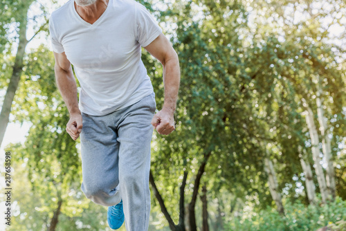 Cropped shot of cheerful senior man starting to jogging in park. Healthy lifestyle concept