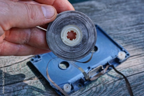 part of an old audio cassette with a brown bobbin film in the fingers