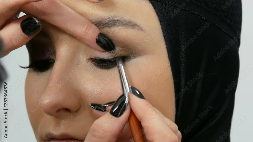 Professional stylist make-up artist makes eye makeup model. Face model with evening make-up close up view Professional stylist make-up artist makes eye makeup model. Face model with evening make-up close up view