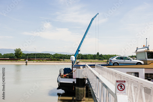 Wallpaper Mural Strasbourg, France - Jun 2, 2013: Rear part of large cargo barge tanker boat transporting car in upper deck transport on Rhine River with Germany Black Forest Mountains in the background Torontodigital.ca
