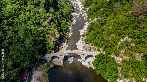 Ancient bridge in the mounbtains with reflection in the water. Devil's bridge - Bulgaria photo