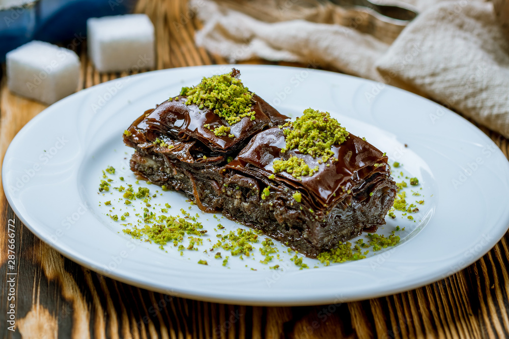 chocolate baklava with pistachios on wooden table. Turkish cuisine chocolate baklava with pistachios on wooden table. Turkish cuisine
