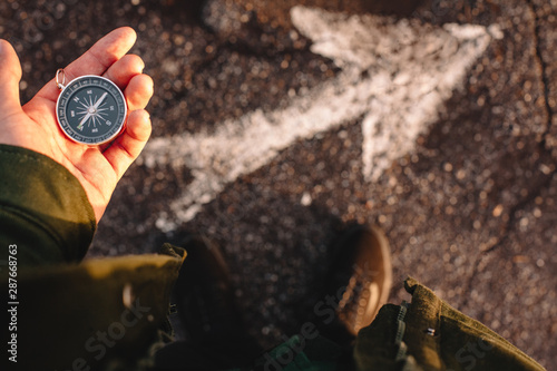 Hipster traveler holding compass in the hand making choice in what direction to go