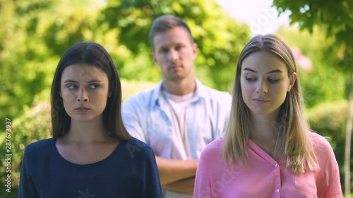 Handsome man choosing between brown-haired and blonde-haired women, competitors