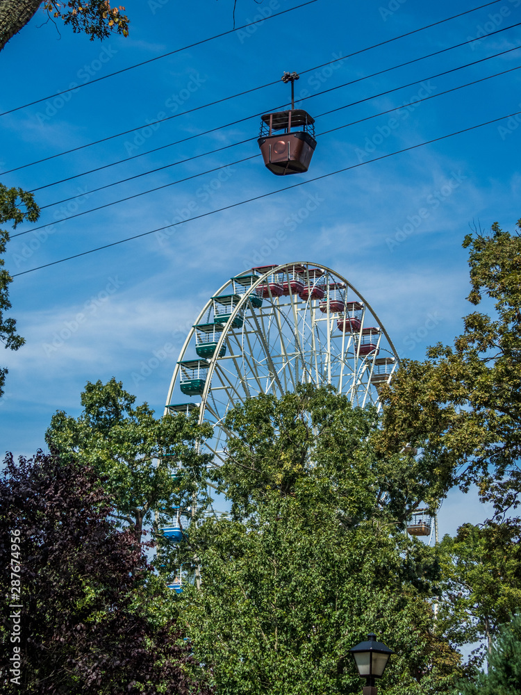 Fototapeta premium Cable car on the foreground and ferris wheel on the background