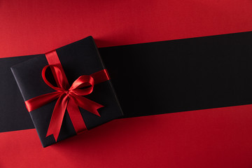 Top view of black christmas boxes with red ribbon on black background with copy space for text. black Friday and Boxing Day composition.