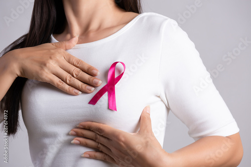 Photo Closeup of pink badge ribbon on woman chest to support breast cancer cause