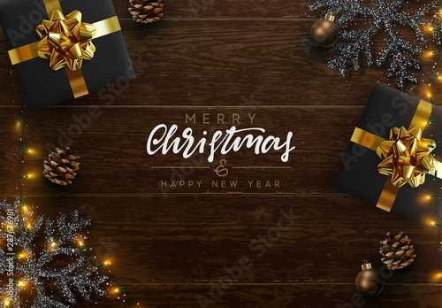 Christmas composition on wooden background. Xmas decoration design, box gift, snowflake color black, gold light garland, pine cone. Brown realistic wood texture. Flat lay, top view.