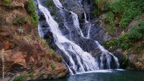 Tilt Up, Slow Motion Waterfall flowing off Rocky Mountain into River at Walter Sisulu National Botanical Garden, Johannesburg, South Africa photo