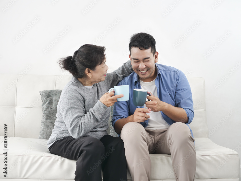 Asian mother and her son talking and drinking at home, lifestyle concept.