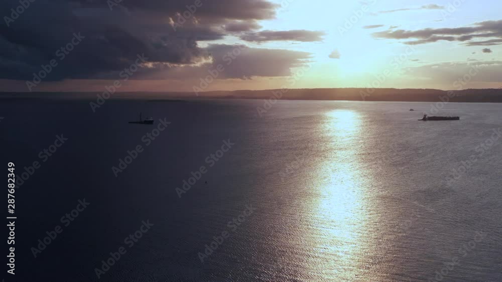 a steady drone camera pan right over Coney Island Creek, viewing the dark golden, cloudy sunset a steady drone camera pan right over Coney Island Creek, viewing the dark golden, cloudy sunset