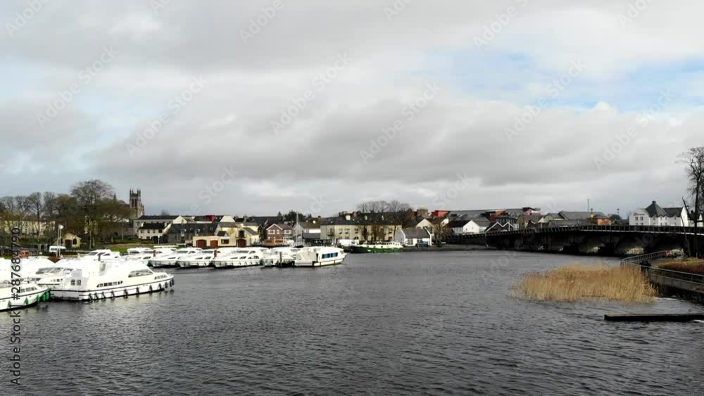 Aerial - Lakeside view in a small town. Nearby the residential area and the park with sidewalk. Bridge mainroad with traffic passing by. Aerial - Lakeside view in a small town. Nearby the residential area and the park with sidewalk. Bridge mainroad with traffic passing by.