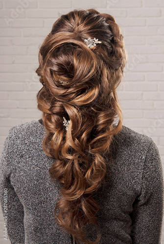 Female hairstyle oriental tail on the head of a brown-haired woman back view.