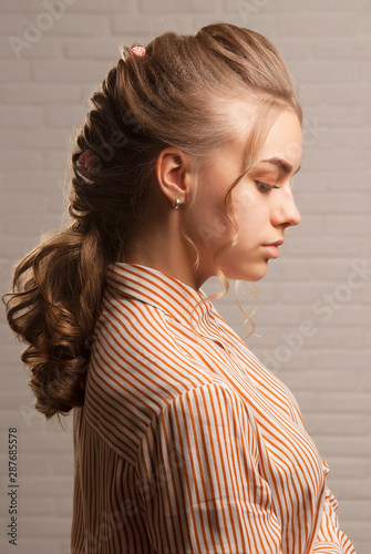 Nice blonde girl with hairstyle and makeup looks down in profile close-up.