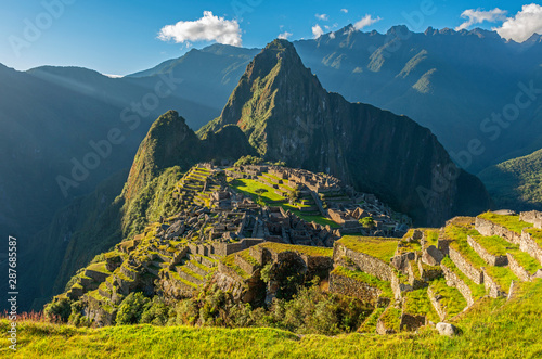 Inca ruin of Machu Picchu at sunset with the last sun rays illuminating the lost city seen from the agriculture terraces, Cusco Region, Peru.