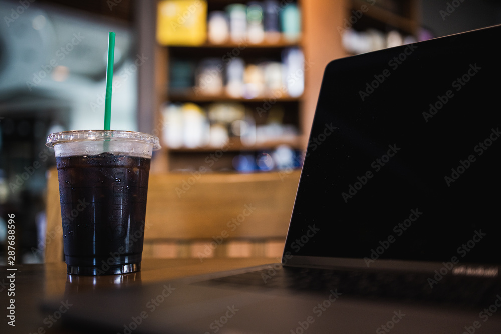Takeaway cup of ice americano coffee with notebook in cafe Takeaway cup of ice americano coffee with notebook in cafe