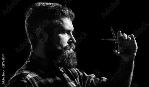 Brutal male, hipster with moustache. Male in barbershop, haircut, shaving. Mans haircut in barber shop. Profile of stylish beard man, scissors. Barber scissors, barber shop. Black and white
