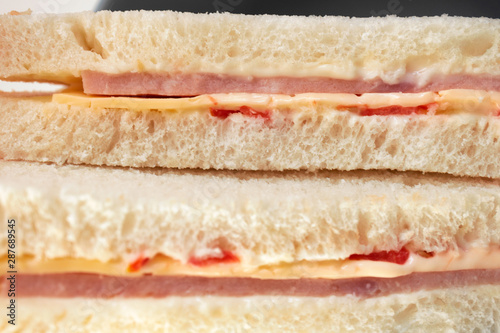 Close-up of cut wheat bread sandwiches with ham, cheese and tomatoes