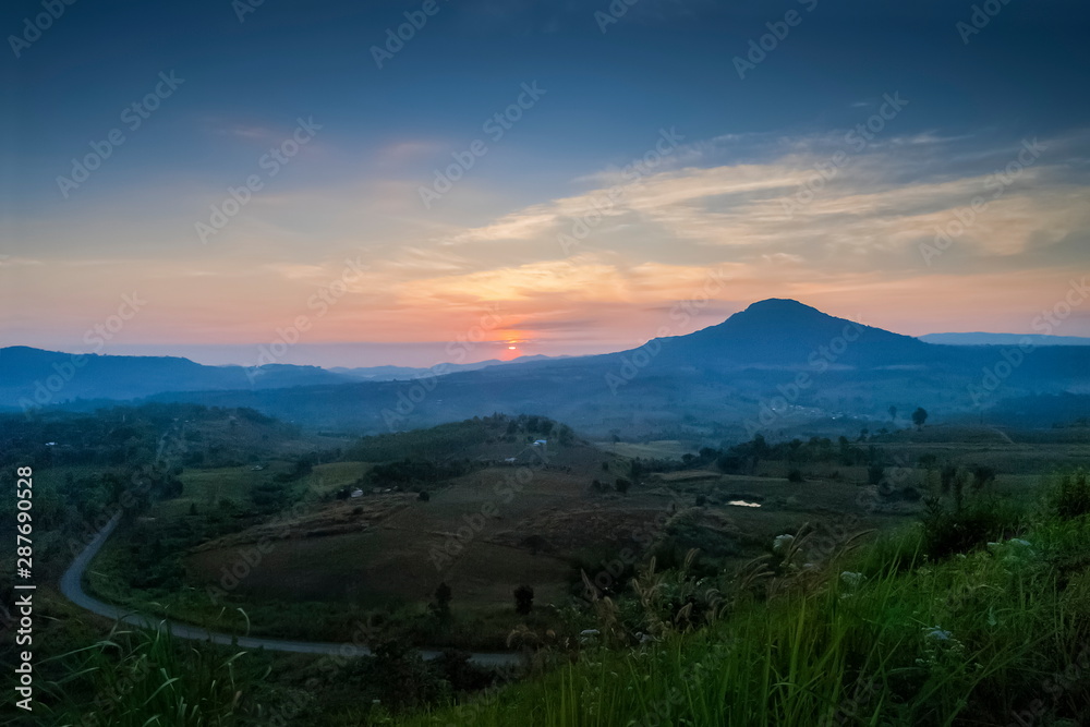 Top view above long road, forest and top hill with red sun light and cloudy sky background, sunrise at Khao Takhian (Takian) Ngo View Point, Khao Kho, Phetchabun, Thailand.