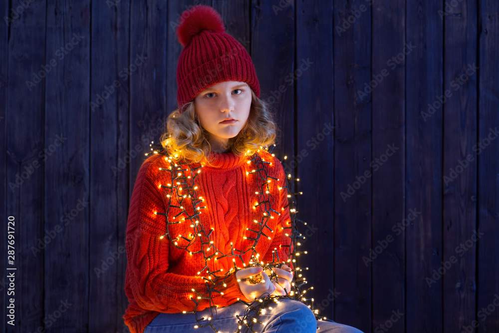 Fototapeta premium girl in red hat with christmas light on wooden background