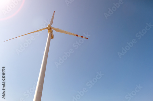 rotating blades of a windmill propeller on blue sky background. Wind power generation. Pure green energy. © hiv360