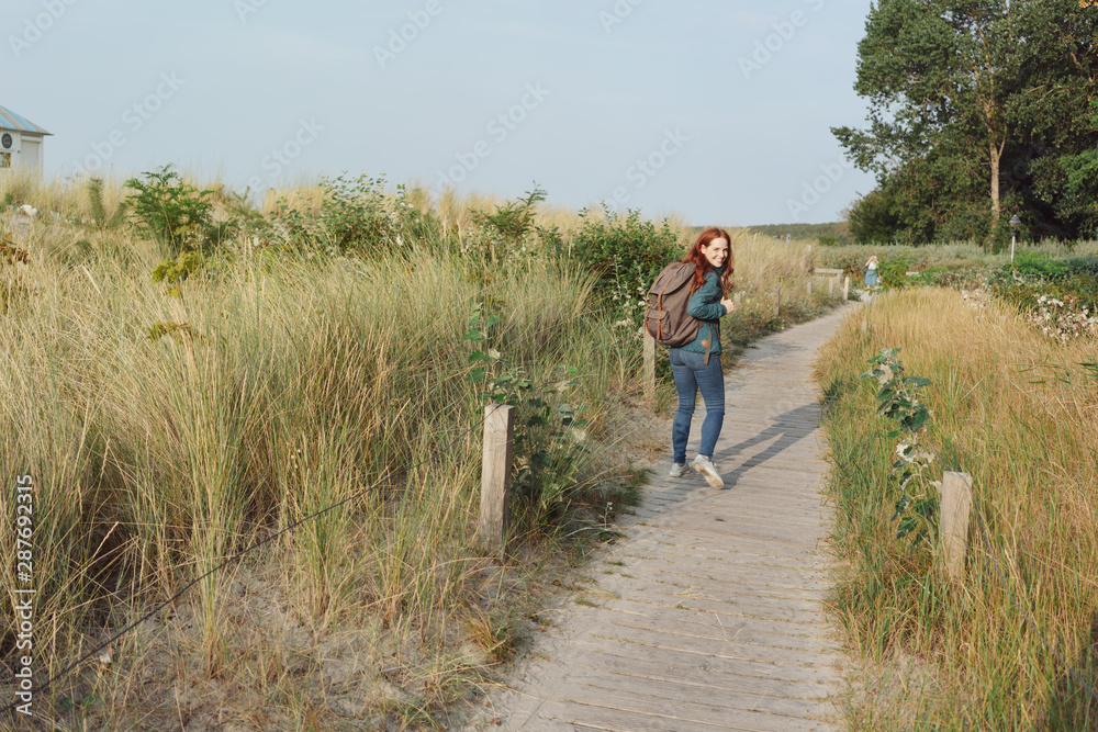 Young woman backpacking on a coastal boardwalk Young woman backpacking on a coastal boardwalk
