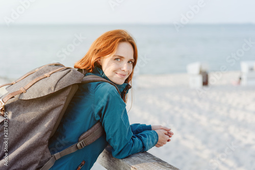 Smiling young woman backpacker at the seaside