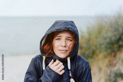 Slika na platnu Freezing cold woman snuggling into her anorak