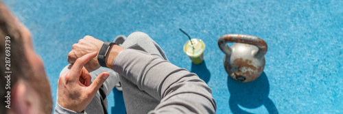 Smartwatch fitness man using watch activity tracker at athletics stadium banner. Closeup of hand with wearable tech lifting weights and drinking juice.