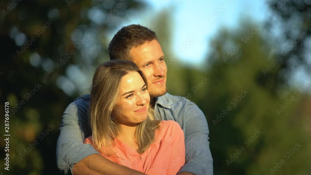 Young smiling couple hugging at sunny park, candy-flower period, true feelings Young smiling couple hugging at sunny park, candy-flower period, true feelings