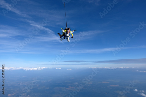 Skydiving. A tandem is in the sky. An young girl and her instructor.