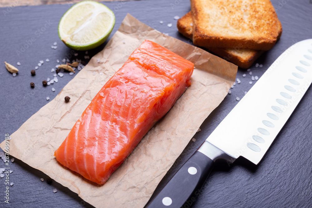 Salmon, avocado, lime and toasts laying with knife on slate background. Salmon, avocado, lime and toasts laying with knife on slate background.