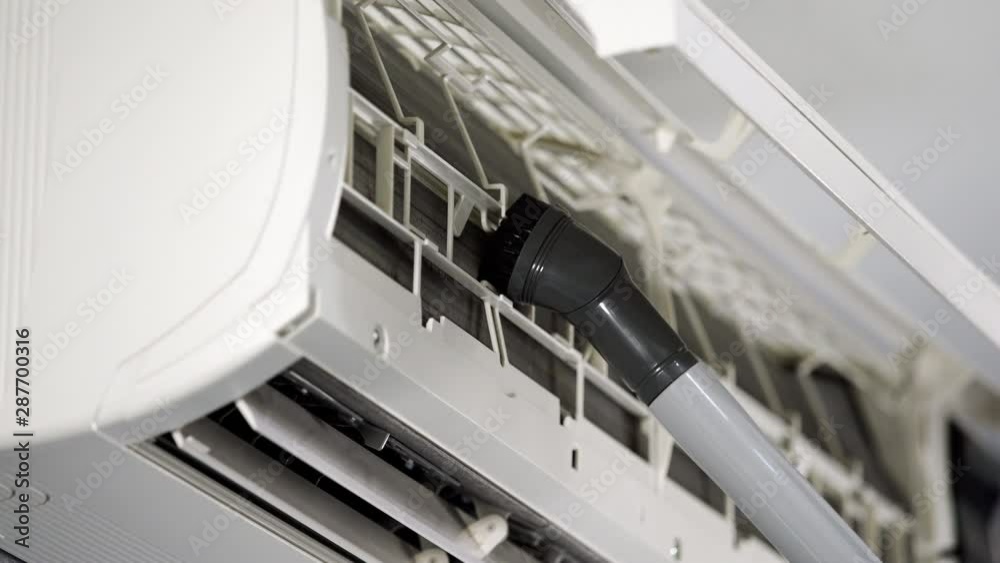 close up technician service using vacuum cleaner to cleaning the air conditioner close up technician service using vacuum cleaner to cleaning the air conditioner