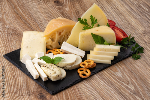 Assortment of various types of cheese on a black stone plate. copy space
