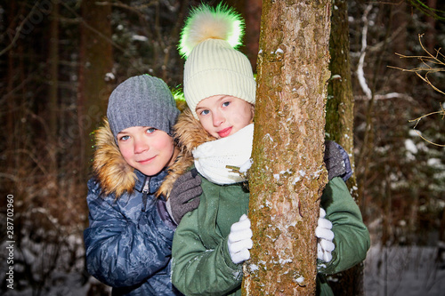 Children boy and girl walking in snow forest in a winter day. Teenagers having trip and rest in weekend outdoor