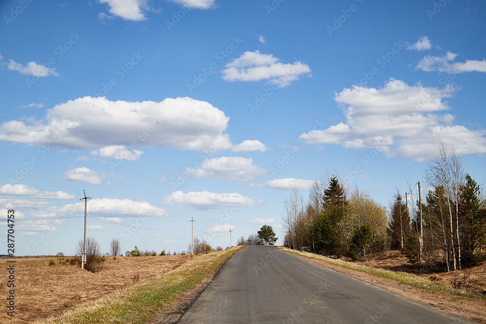Nature landscape with road, blue sky and white clouds in a spring or autumn day. Travel and Journey concept Nature landscape with road, blue sky and white clouds in a spring or autumn day. Travel and Journey concept