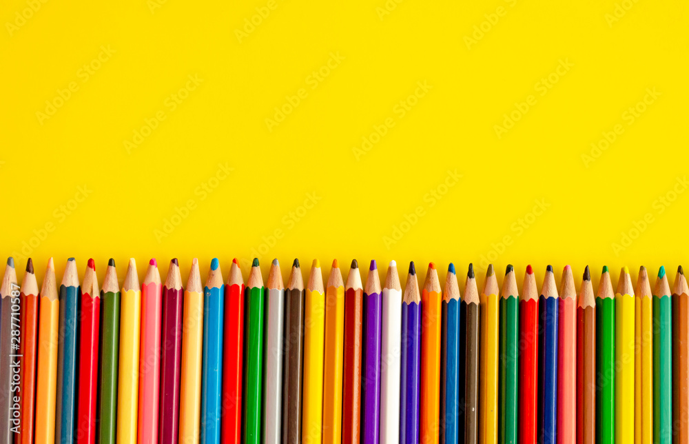 Crayons on yellow background with copy space. Back to school. Colored pencils next to each other top view. Marketing and development theme. Crayons on yellow background with copy space. Back to school. Colored pencils next to each other top view. Marketing and development theme.