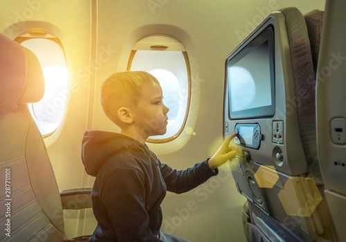 Adorable little boy traveling by airplane. Child sitting by airc photo