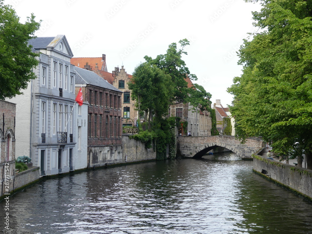Bruges, Belgium - May 2019: View of the water channel in the city center. Boat trip along the water canals of the city. Bruges, Belgium - May 2019: View of the water channel in the city center. Boat trip along the water canals of the city.