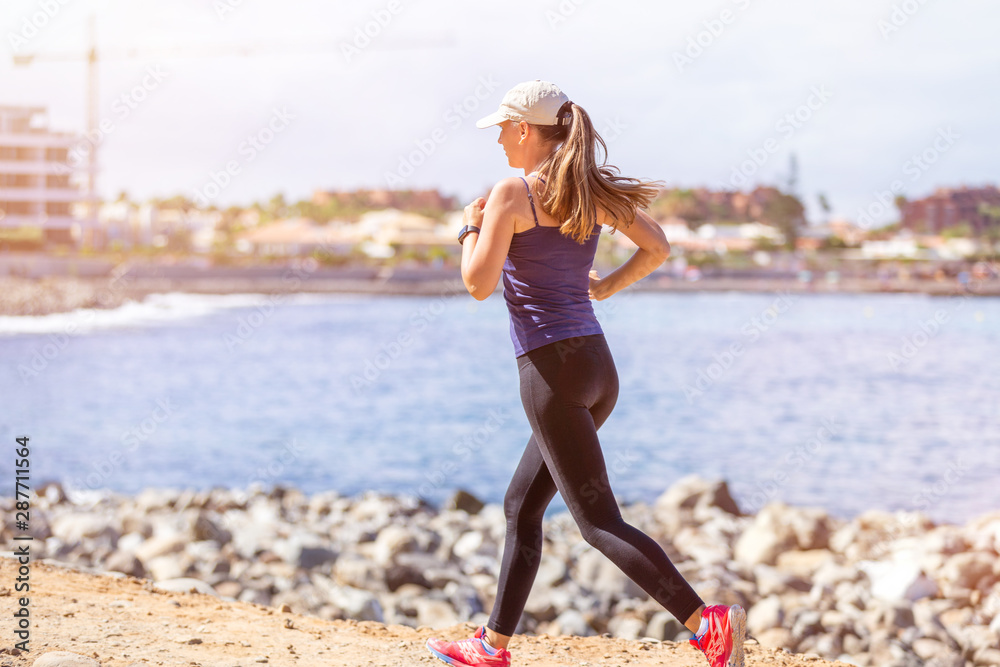 Young slim woman running near sea in the morning