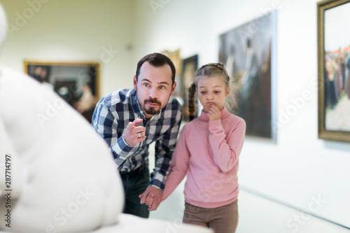 Father and daughter looking at classical statues