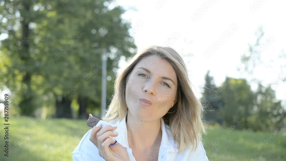 portrait of a beautiful woman in the park who eats chocolate candy portrait of a beautiful woman in the park who eats chocolate candy