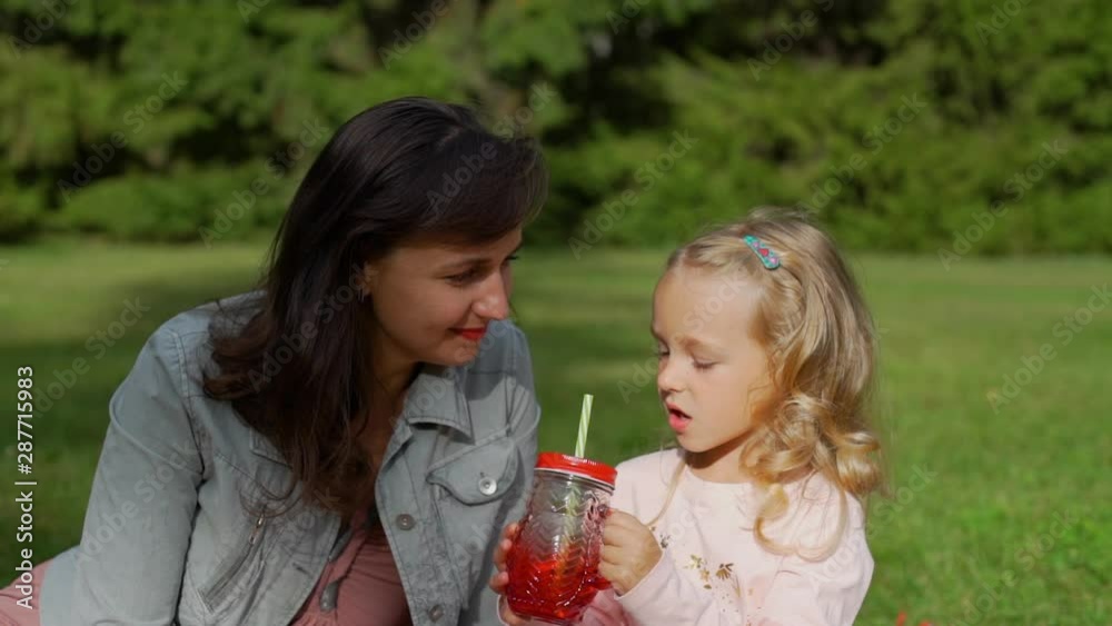 Young Woman and Cute Little Girl Talking While Having Picnic in Summer Park. Family, Leisure and People Concept Young Woman and Cute Little Girl Talking While Having Picnic in Summer Park. Family, Leisure and People Concept