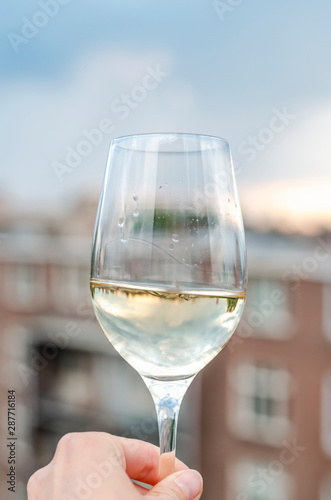 A glass of white wine in her hand.