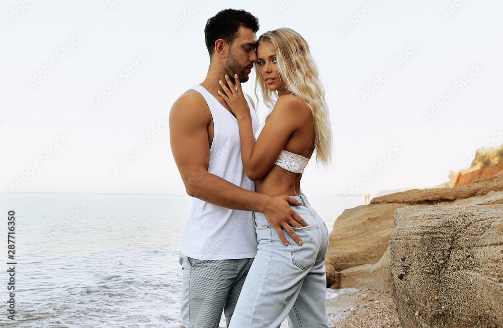 beautiful lovely couple wearing jeans,posing at summer beach - obrazy, fototapety, plakaty 