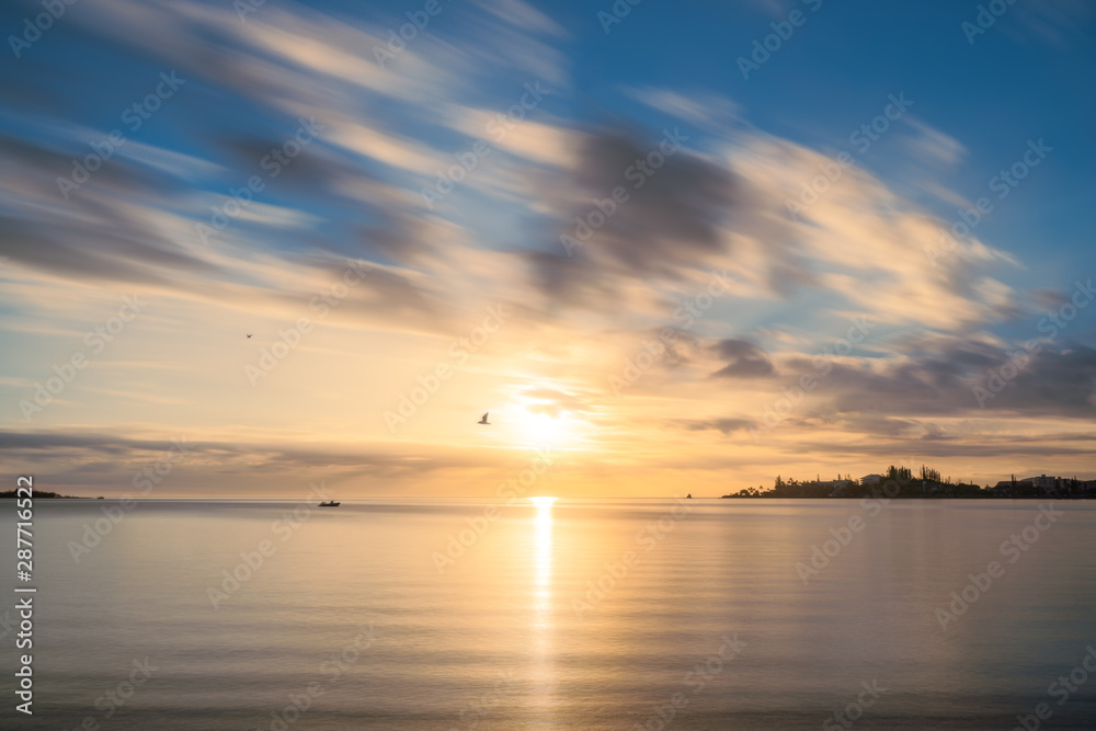 Birds flying at goden hour at Anse Vata Bay in New Caledonia, French Polynesia, South Pacific. Long exposure image.
