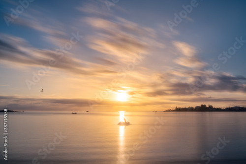 A Jet ski stops to admire the Sunset at Anse Vata Bay in New Caledonia in French Polynesia, South Pacific. Long exposure image..